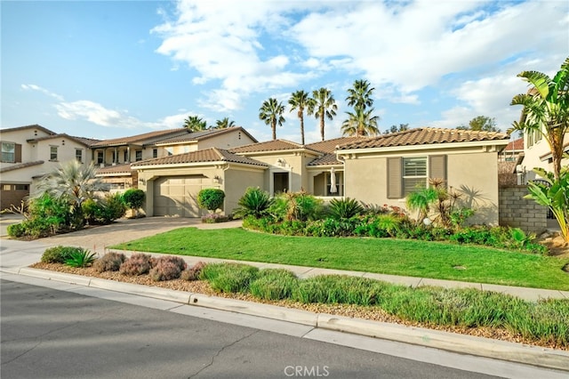 mediterranean / spanish-style house featuring a garage and a front yard