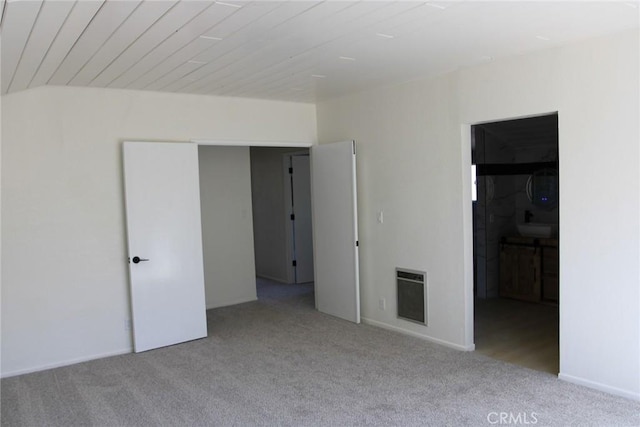 spare room with heating unit and light colored carpet