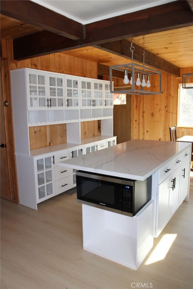 kitchen featuring a kitchen island, white cabinets, and wood walls