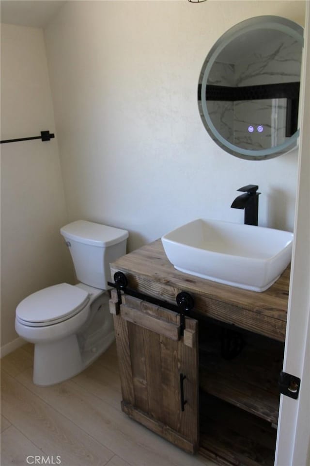 bathroom featuring vanity, wood-type flooring, and toilet