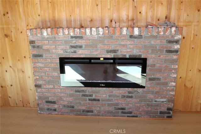 room details featuring hardwood / wood-style floors, a brick fireplace, and wood walls