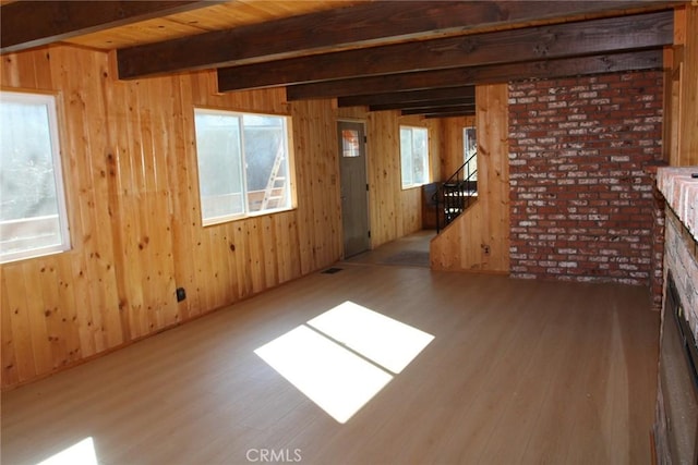 unfurnished living room featuring wood ceiling, wooden walls, a brick fireplace, beamed ceiling, and light wood-type flooring