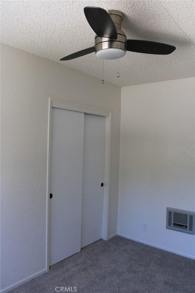 unfurnished bedroom featuring dark colored carpet, a textured ceiling, ceiling fan, and a closet