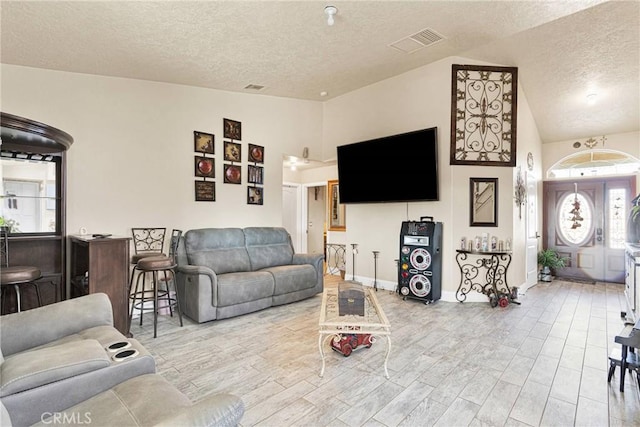 living room with lofted ceiling, a textured ceiling, and light hardwood / wood-style floors