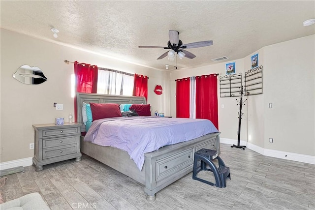 bedroom featuring ceiling fan, a textured ceiling, and light wood-type flooring