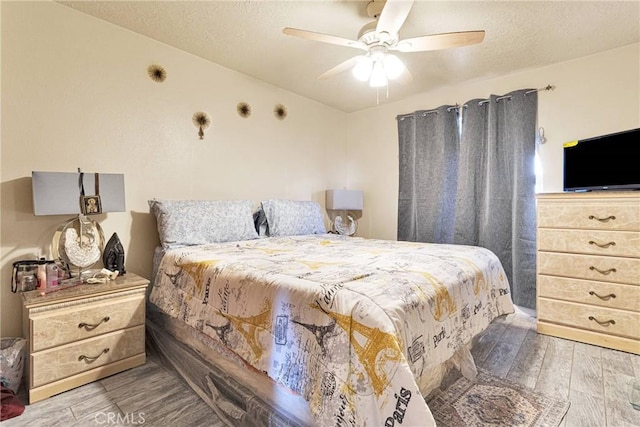 bedroom featuring ceiling fan, hardwood / wood-style floors, and a textured ceiling