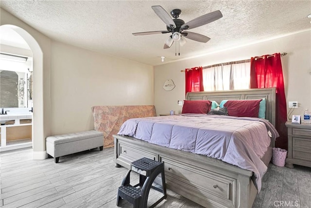 bedroom featuring ceiling fan, light hardwood / wood-style floors, and a textured ceiling