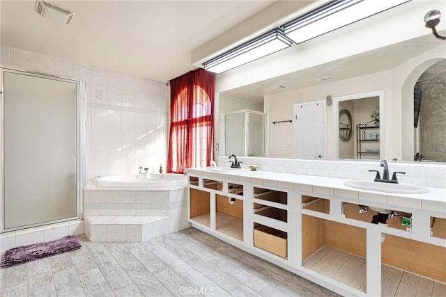 bathroom featuring plus walk in shower, wood-type flooring, and sink