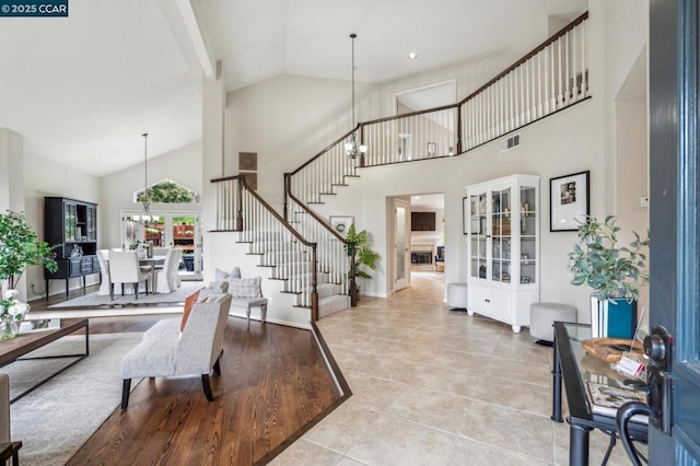 tiled living room featuring a chandelier and high vaulted ceiling