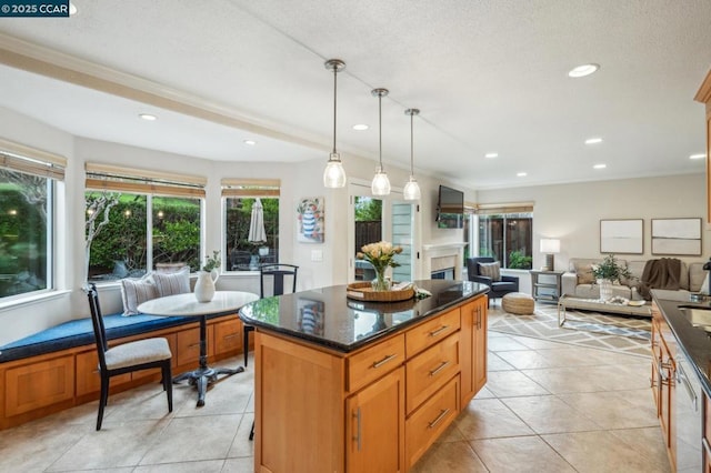 kitchen with decorative light fixtures, light tile patterned floors, a kitchen island, and dark stone countertops