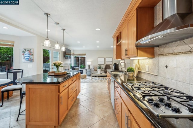 kitchen with plenty of natural light, a center island, wall chimney exhaust hood, and appliances with stainless steel finishes