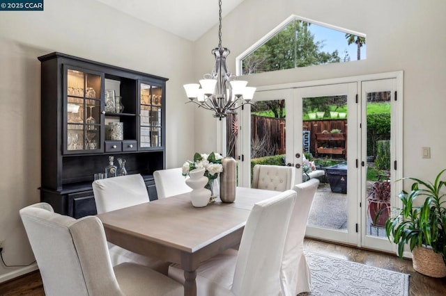 dining room featuring lofted ceiling, dark wood-type flooring, a notable chandelier, and french doors