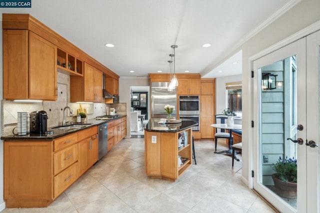 kitchen with pendant lighting, sink, appliances with stainless steel finishes, backsplash, and a center island