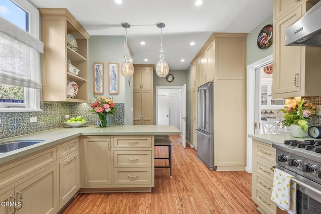 kitchen featuring pendant lighting, a breakfast bar area, premium appliances, ventilation hood, and light hardwood / wood-style floors