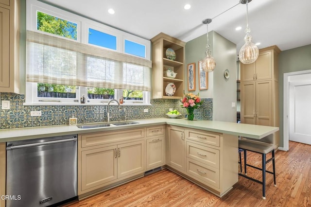 kitchen with sink, stainless steel dishwasher, a kitchen breakfast bar, kitchen peninsula, and pendant lighting