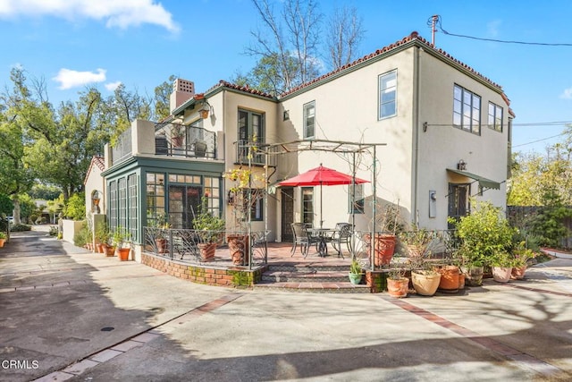 rear view of house with a balcony, a sunroom, and a patio area