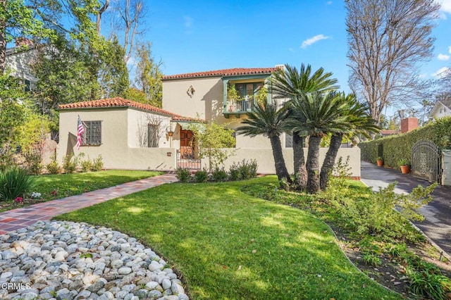 mediterranean / spanish-style home featuring a front yard and a balcony