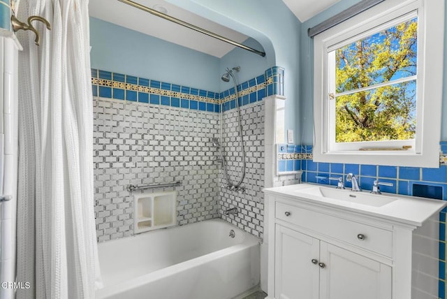 bathroom with vanity, shower / bathtub combination with curtain, and tile walls