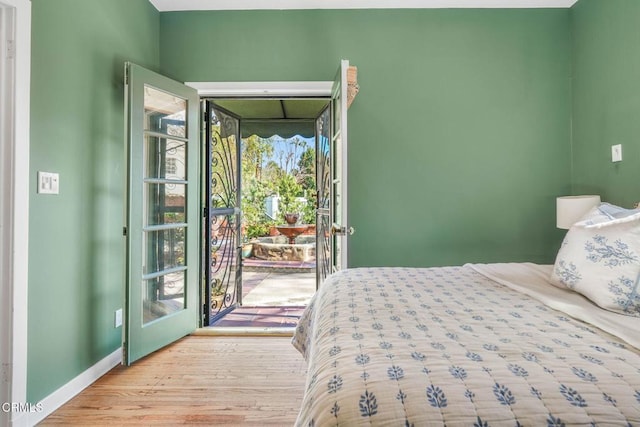 bedroom featuring multiple windows, access to outside, and light hardwood / wood-style flooring