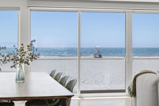 sunroom / solarium featuring a water view and a beach view