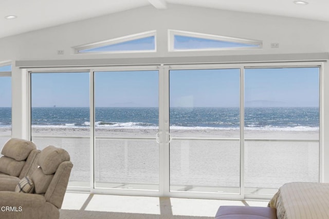 sunroom featuring vaulted ceiling, a water view, and a view of the beach