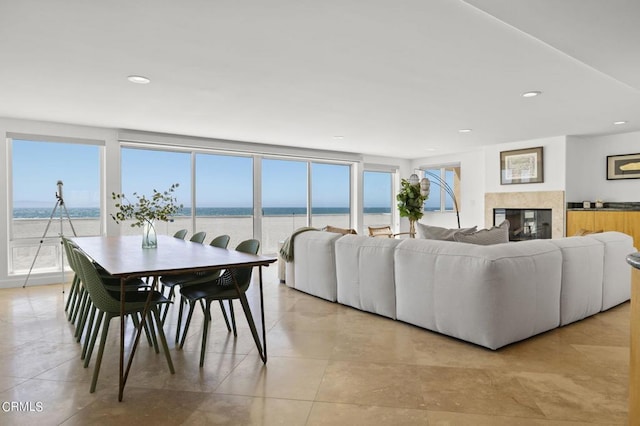 living room with light tile patterned flooring, a premium fireplace, and a water view