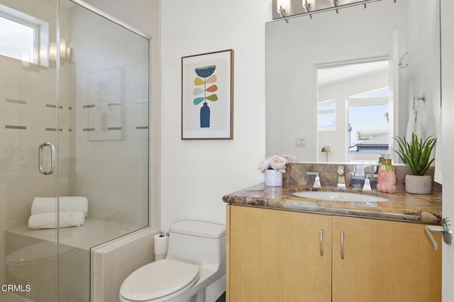 bathroom featuring vanity, toilet, and a shower with door