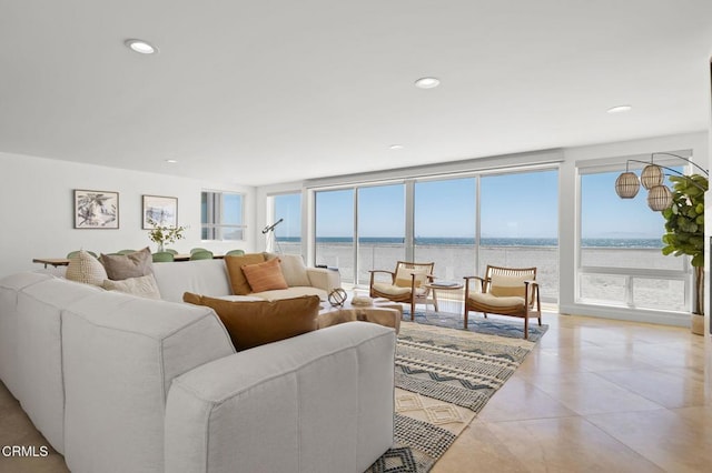 living room with light tile patterned floors, a wealth of natural light, floor to ceiling windows, and a water view