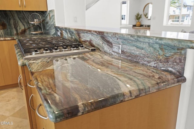 room details featuring dark stone counters, stainless steel gas cooktop, and decorative backsplash