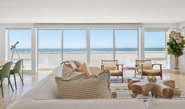 tiled living room with a water view and a view of the beach