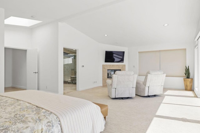 bedroom featuring ensuite bath, a high end fireplace, vaulted ceiling with skylight, and light carpet