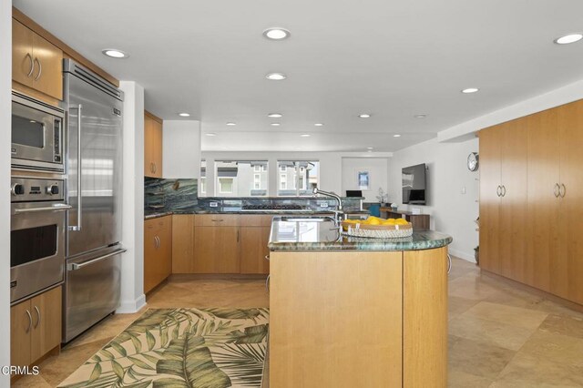 3757 Ocean Dr, Oxnard, CA 93035 - kitchen with appliances with stainless steel finishes, recessed lighting, backsplash, an island with sink, and brown cabinetry