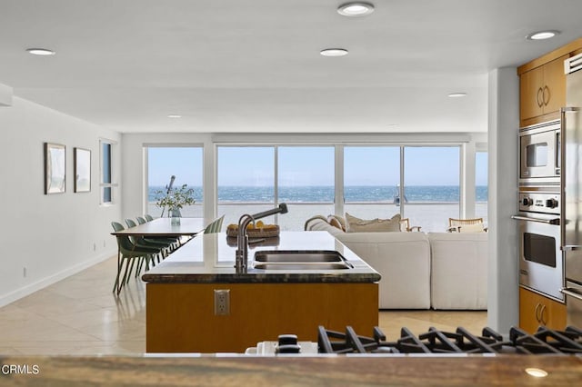 3757 Ocean Dr, Oxnard, CA 93035 - kitchen featuring stainless steel appliances, recessed lighting, a water view, brown cabinets, and a center island with sink
