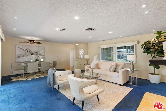 carpeted living room featuring ceiling fan and a textured ceiling