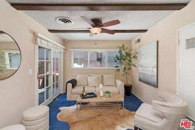 interior space featuring beamed ceiling, ceiling fan, and a textured ceiling