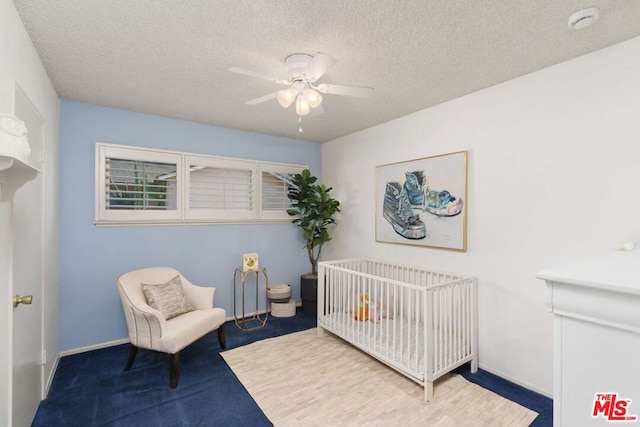 bedroom featuring a crib, carpet floors, and a textured ceiling