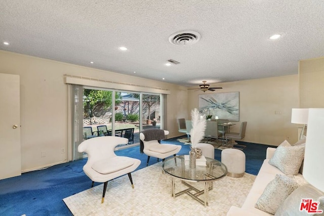 living room featuring ceiling fan, carpet floors, and a textured ceiling