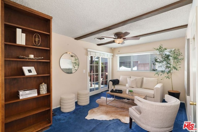 carpeted living room with ceiling fan and a textured ceiling