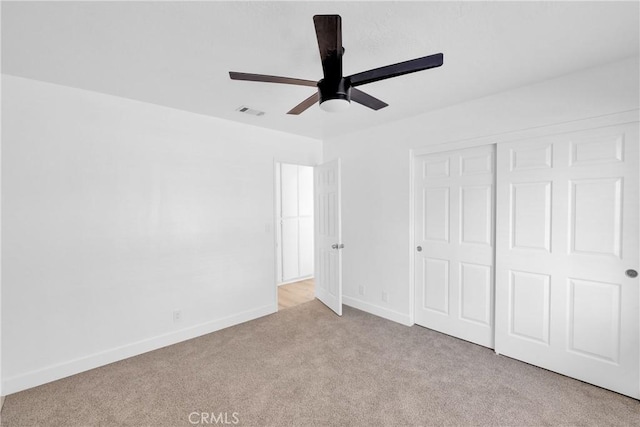 unfurnished bedroom with light colored carpet, ceiling fan, and a closet