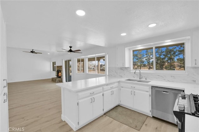 kitchen featuring tasteful backsplash, sink, white cabinets, stainless steel dishwasher, and kitchen peninsula