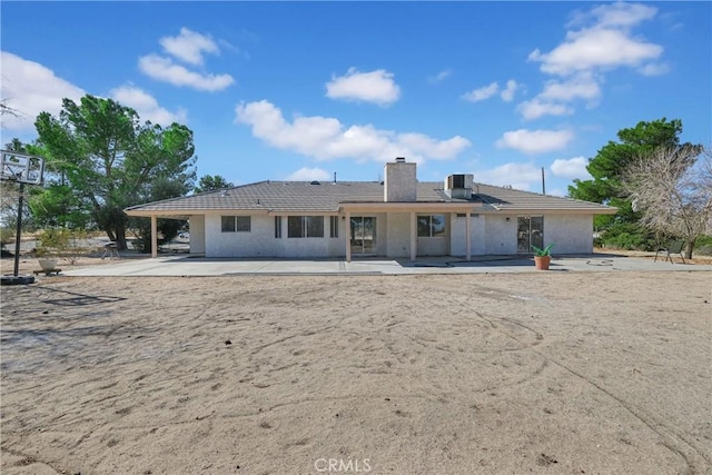 back of property with central AC and a patio