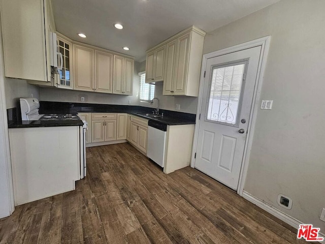 kitchen with dark wood-type flooring, cream cabinets, dishwashing machine, and sink