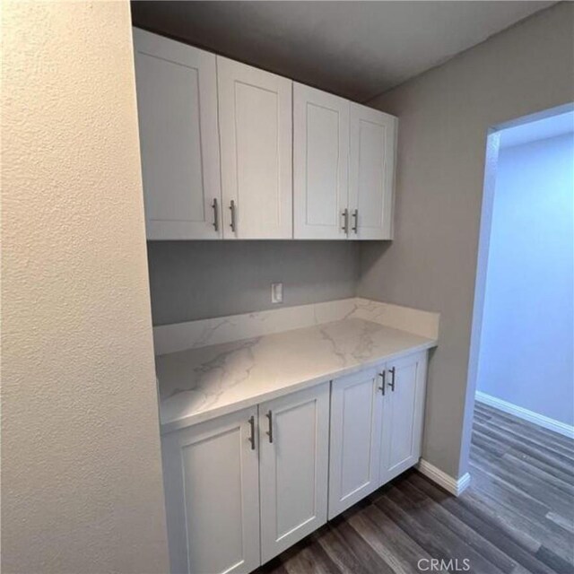 kitchen with white cabinetry, dark wood-type flooring, and light stone counters