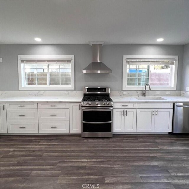 kitchen featuring sink, white cabinetry, dark hardwood / wood-style floors, stainless steel appliances, and wall chimney range hood