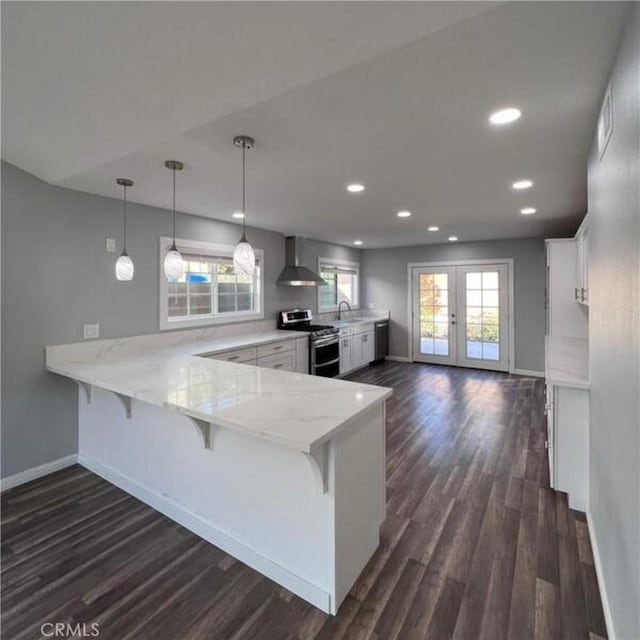 kitchen featuring hanging light fixtures, white cabinets, double oven range, a peninsula, and a kitchen breakfast bar