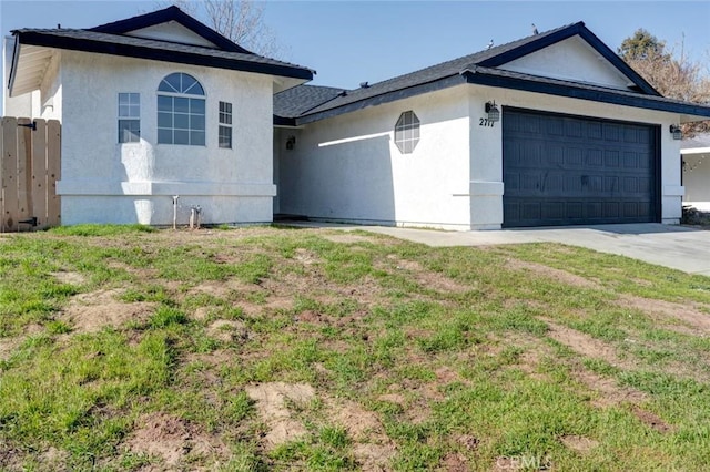 view of front of property featuring driveway, a front lawn, an attached garage, and stucco siding