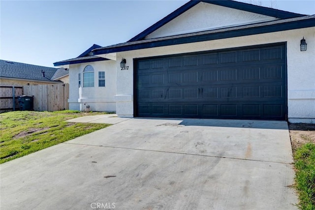 view of front of house featuring a garage, driveway, fence, and stucco siding