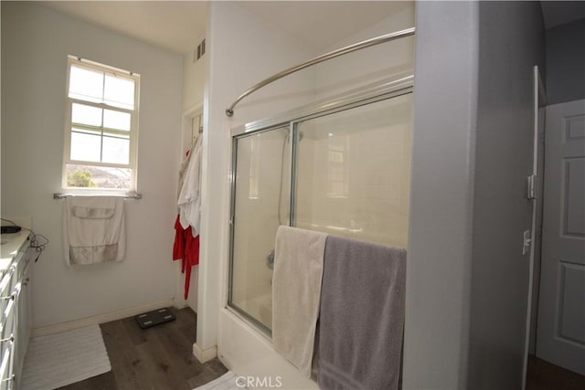 bathroom with wood-type flooring, vanity, and shower / bath combination with glass door