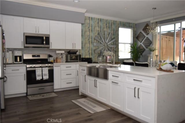 kitchen with ornamental molding, stainless steel appliances, hanging light fixtures, and white cabinets