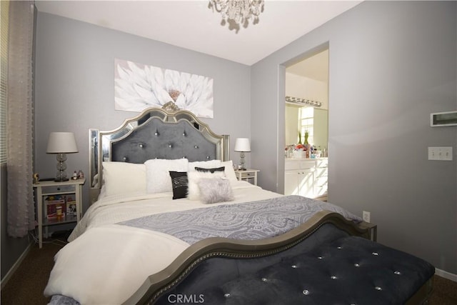 bedroom with an inviting chandelier, ensuite bathroom, and dark carpet